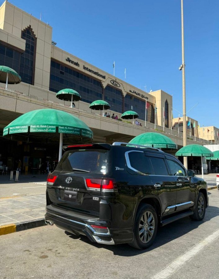 Professional chauffeur standing by a luxury vehicle for international traveler transport, provided by Karachi Rental Car